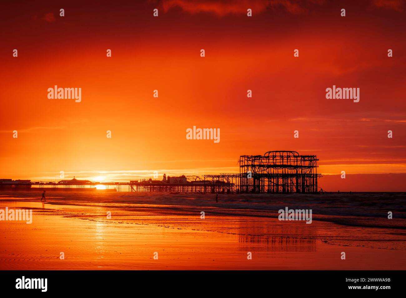 Brighton West Pier und Palace Pier während eines sehr lebhaften roten Sonnenaufgangs an der Ostküste von Sussex im Südosten Englands Großbritannien Stockfoto