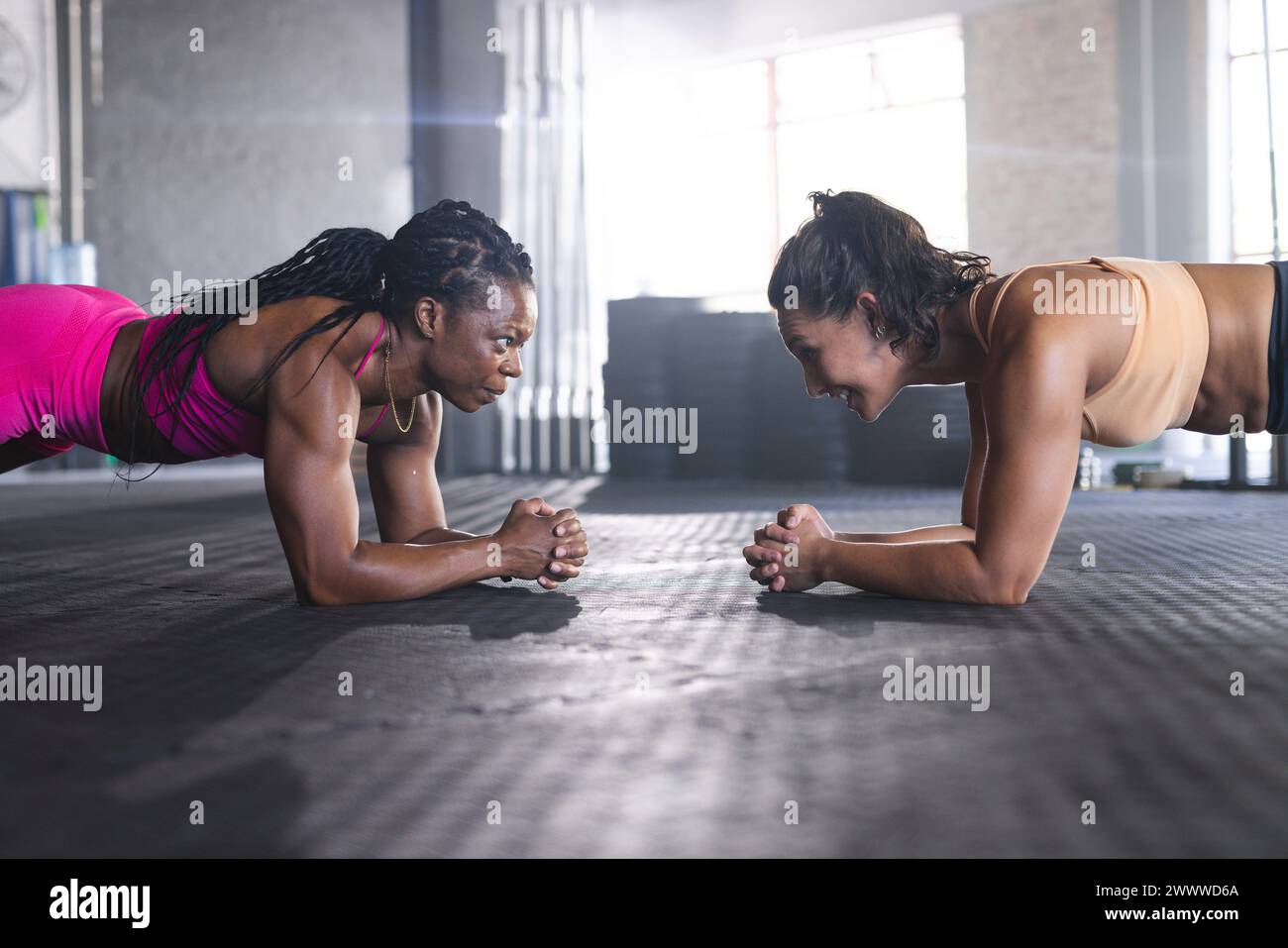 Zwei Frauen nehmen im Fitnessstudio an einer Plank-Übung Teil und zeigen Konzentration und Kraft Stockfoto