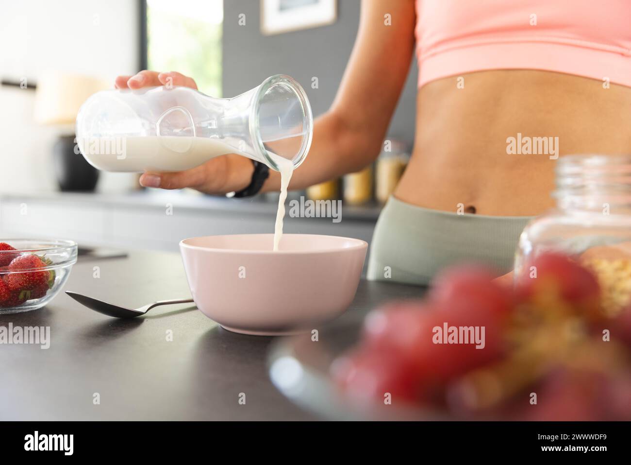 Eine Person gießt Milch zum Frühstück in eine Schüssel Stockfoto