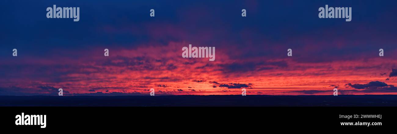 Feuer auf dem Himmel: Aus der Luft, langer Panoramablick auf farbenfrohe, orange und rote Streifen von Zirruswolken am tiefblauen Abendhimmel. Ideal für SKY Re Stockfoto