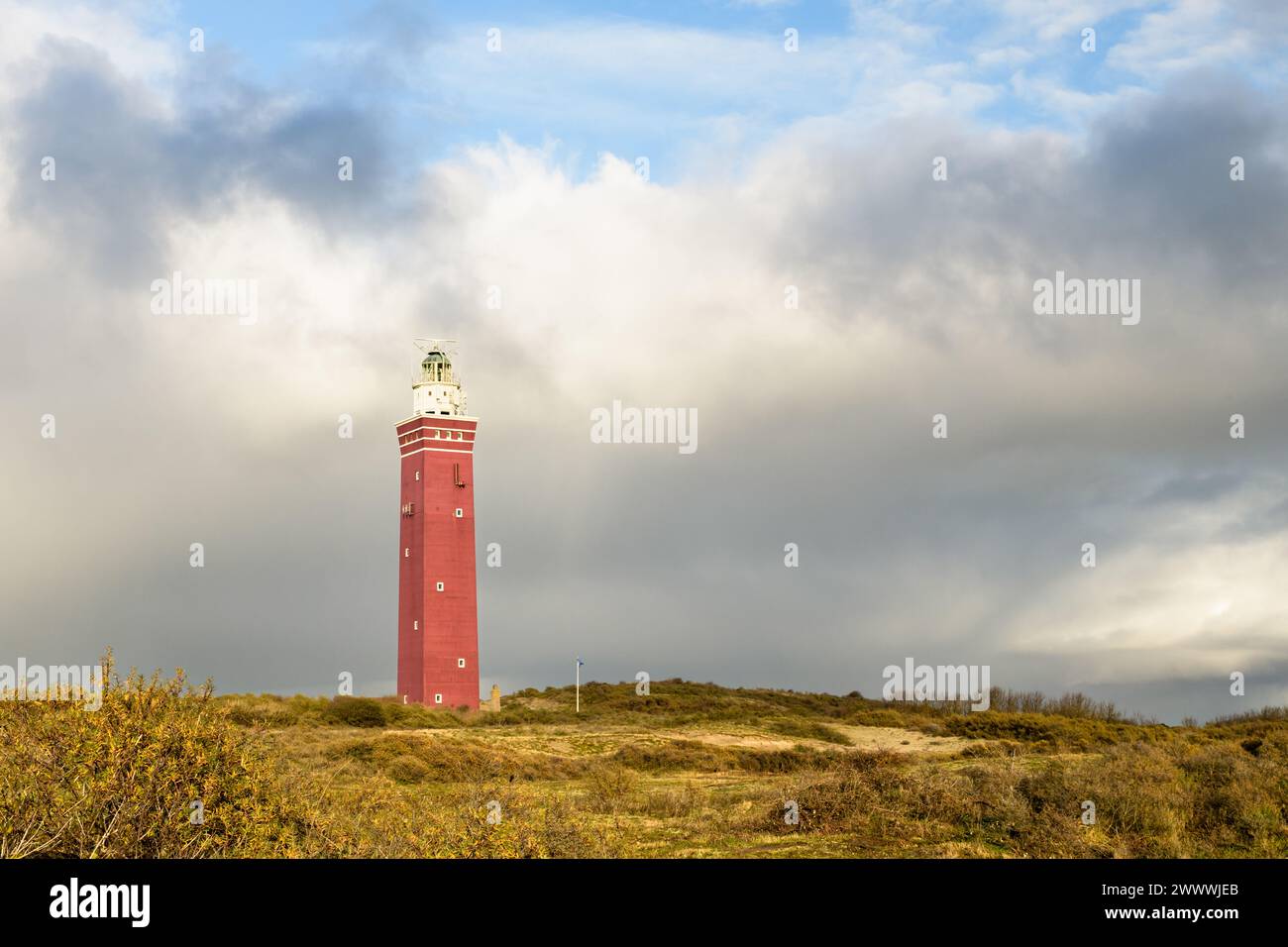 Der rote Backsteinleuchtturm Westhoofd liegt in den Dünen von Ouddorp und steht in der Sonne unter einem wunderschönen Himmel mit Wolken nahe der Nordseeküste Stockfoto