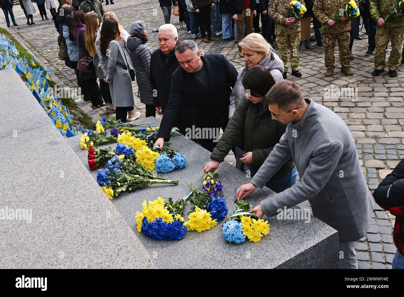 Nicht exklusiv: LEMBERG, UKRAINE - 25. MÄRZ 2024 - Menschen legen Blumen am Denkmal für den Helden der Ukraine, Führer der Volksbewegung Ukr Stockfoto