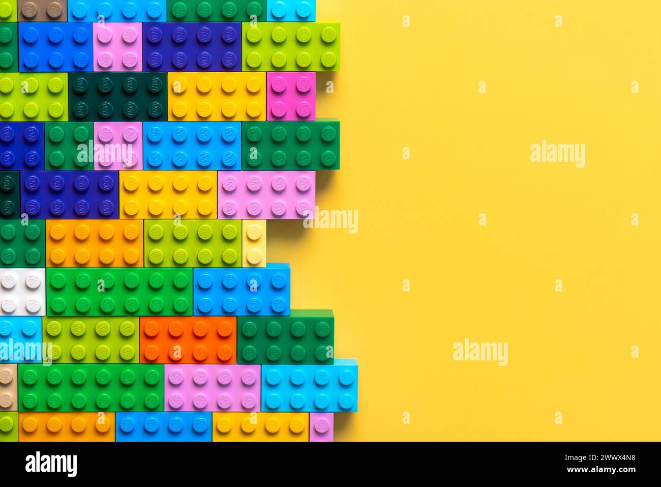 Nahaufnahme von bunten Lego-Blöcken mit Platz für Text auf gelbem Hintergrund. Illustrativer Leitartikel Stockfoto