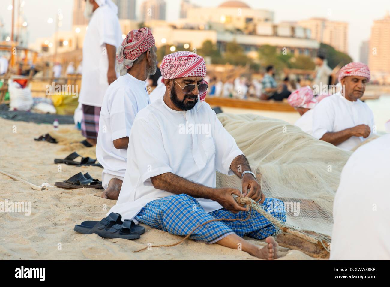Ein arabischer Mann repariert das Fischernetz während des Dhow Festivals im Dorf Katara. Stockfoto