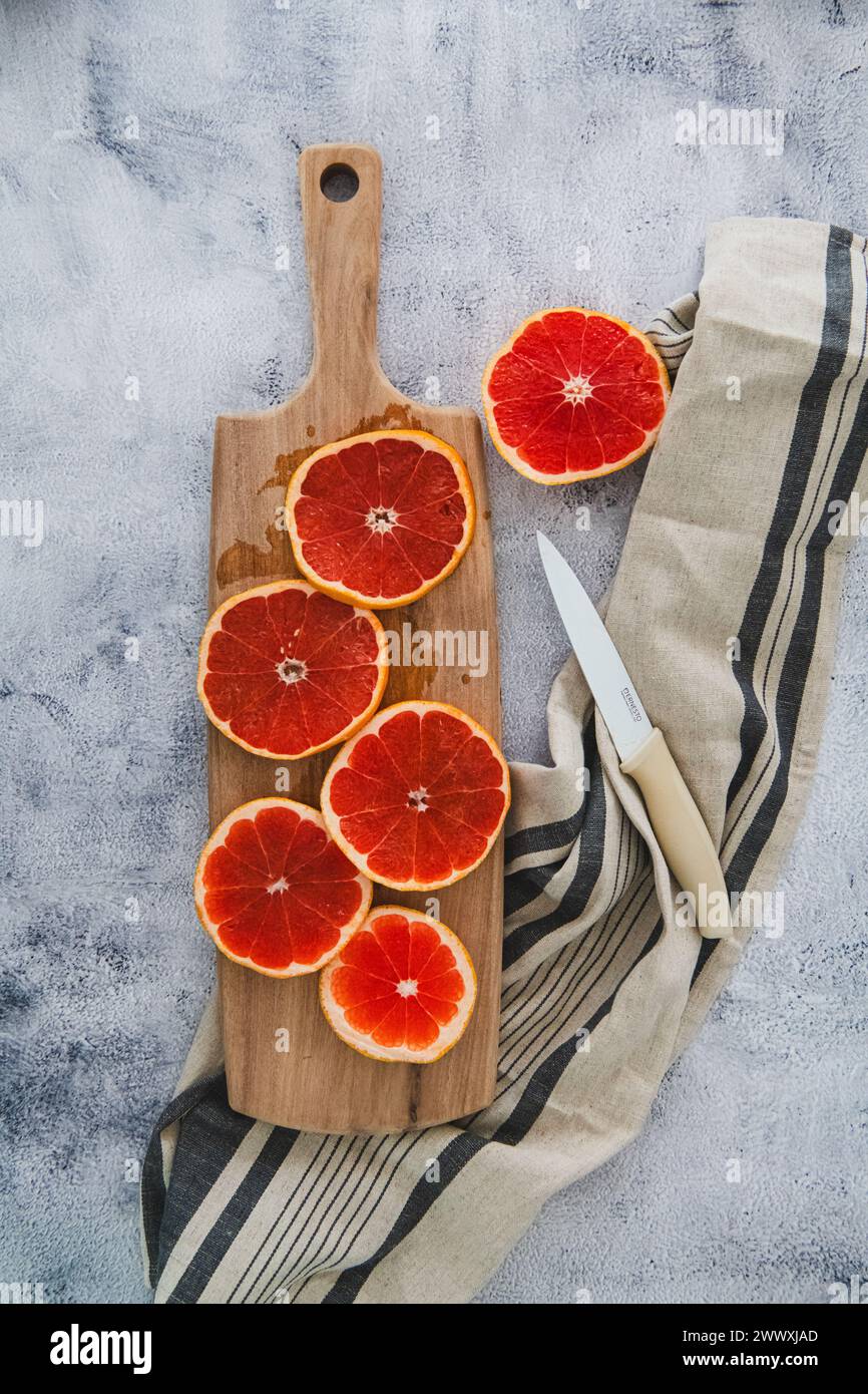Grapefruit auf Akazienholz Schneidebrett mit Leinenserviette und Messer Stockfoto