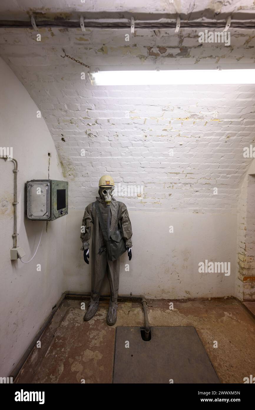 26. März 2024, Sachsen, Kšnigstein: Eine Schaufensterpuppe mit Schutzanzug und Gasmaske steht in einer Ecke während des Presserundgangs der neuen Ausstellung 'Nuklearbunker und Pulvermagazin' im ehemaligen Bunker für den DDR-Zivilschutz. Die Festung Königstein macht Räume des einst geheimen DDR-Bunkers im Festungswald, die in der Ausstellung selten zu sehen sind, im Rahmen von Führungen zugänglich. Foto: Robert Michael/dpa Stockfoto