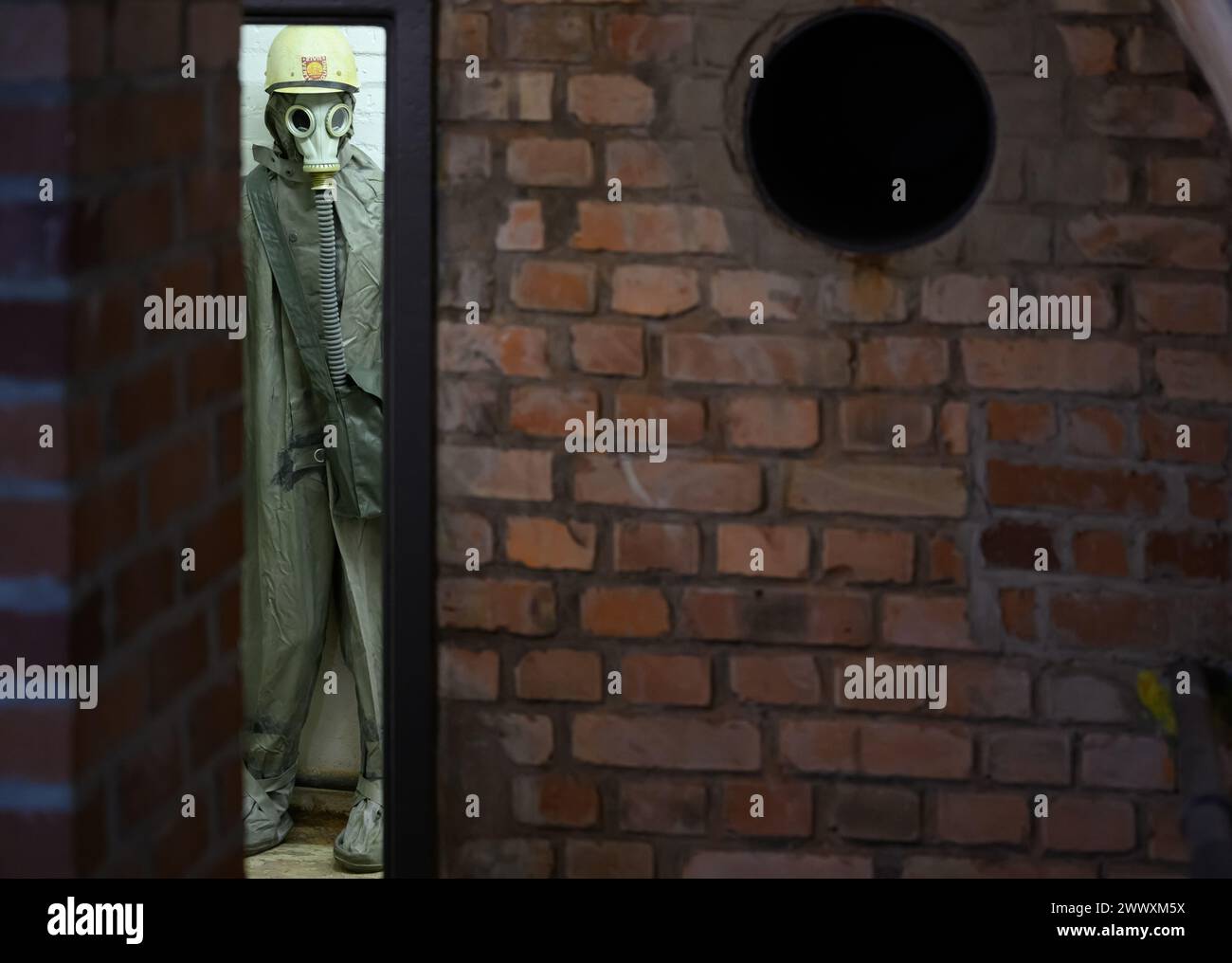 26. März 2024, Sachsen, Kšnigstein: Eine Schaufensterpuppe mit Schutzanzug und Gasmaske steht in einer Ecke während des Presserundgangs der neuen Ausstellung 'Nuklearbunker und Pulvermagazin' im ehemaligen Bunker für den DDR-Zivilschutz. Die Festung Königstein macht Räume des einst geheimen DDR-Bunkers im Festungswald, die in der Ausstellung selten zu sehen sind, im Rahmen von Führungen zugänglich. Foto: Robert Michael/dpa Stockfoto