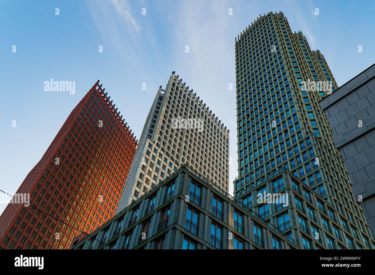 Vertikale Ansicht der Wolkenkratzer im zentralen Haag-Viertel, Niederlande. Morgenlicht, blauer Himmel mit dünnen Wolken. Farbenfrohe moderne Gebäude... Stockfoto