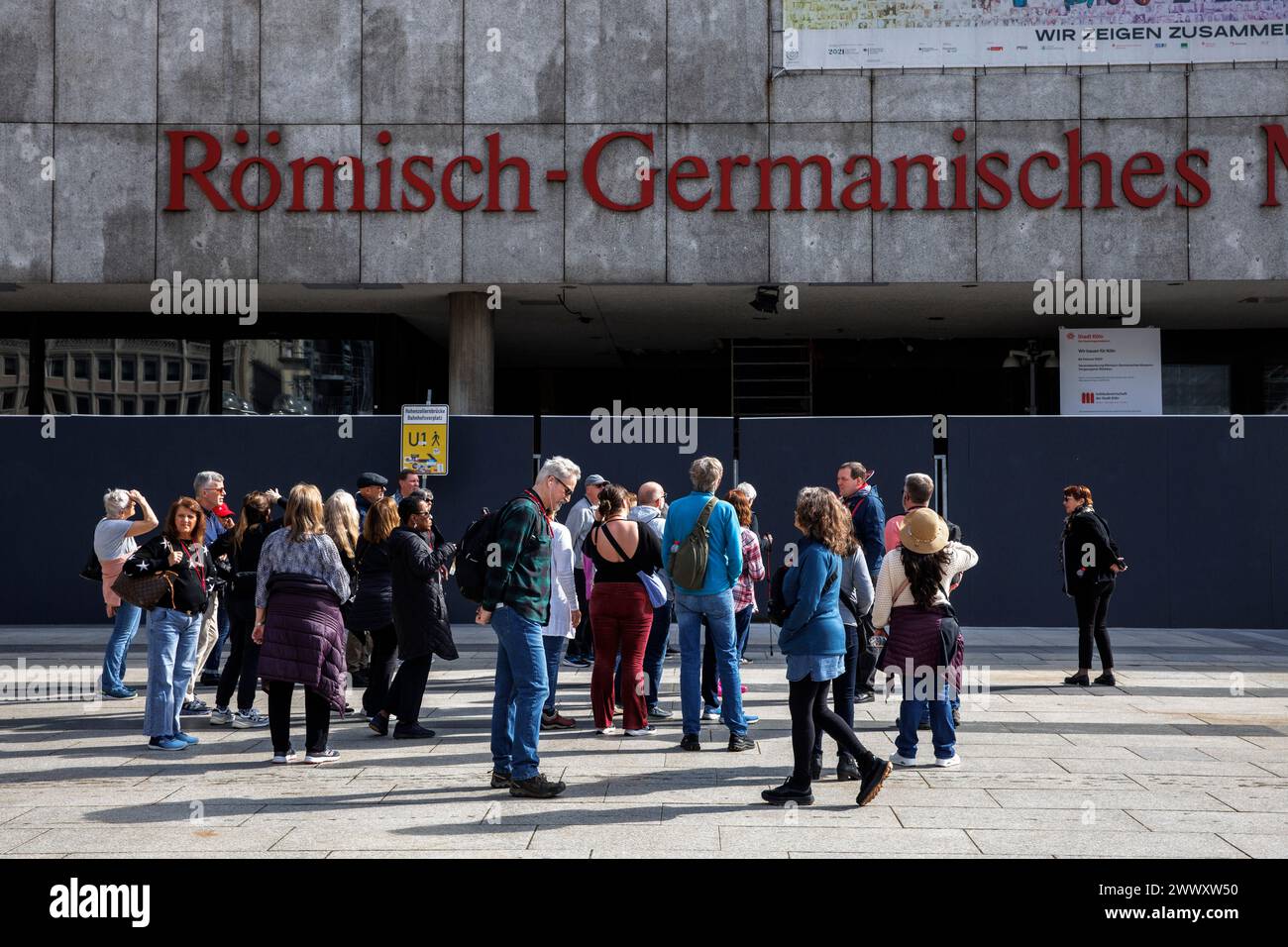 Eine Gruppe von Touristen steht vor einem Bauzaun im Römisch-Germanischen Museum am Roncalli-Platz in Köln. 20.03.2024 eine Touris Stockfoto