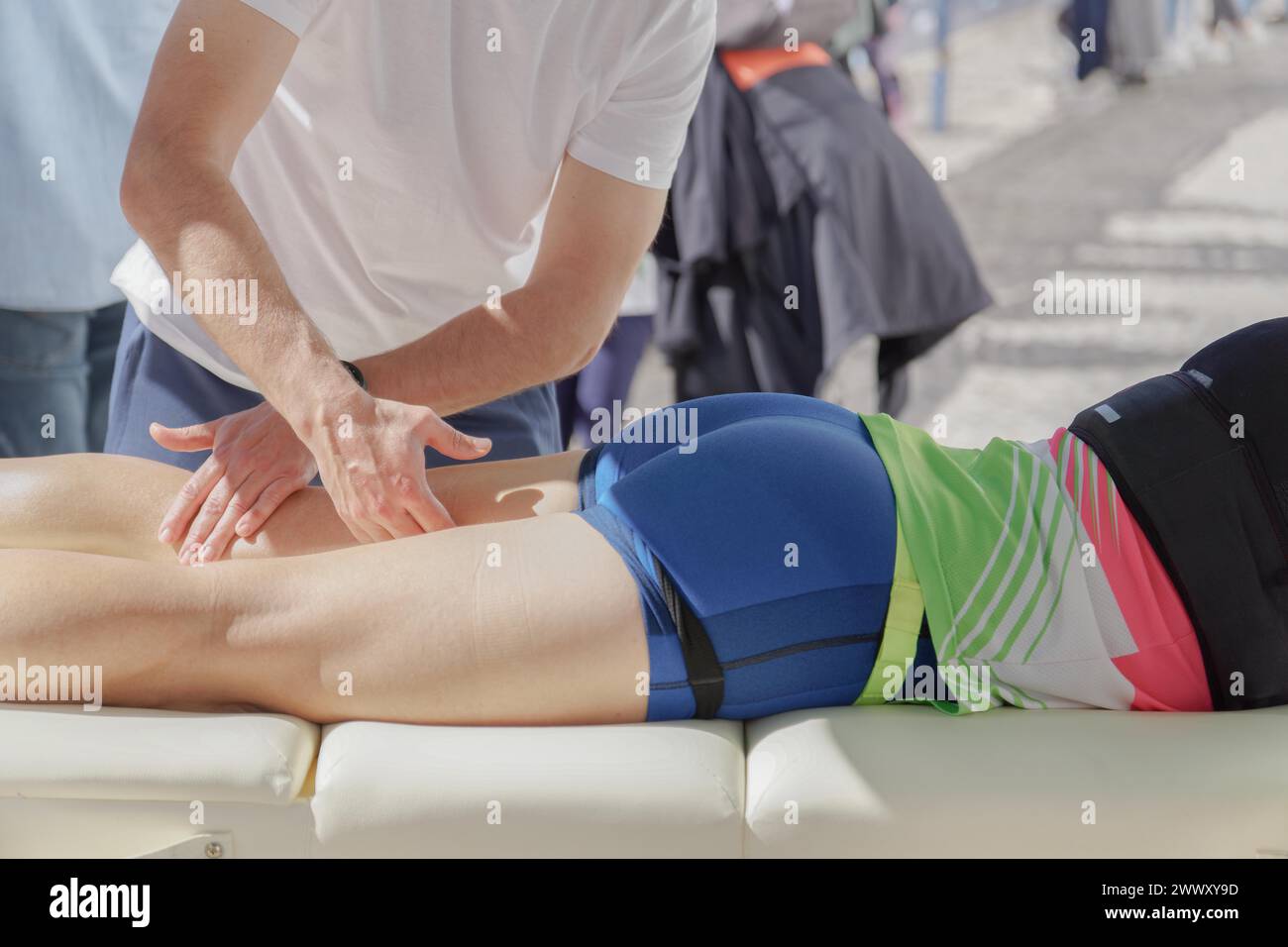 Ein Ersthelfer leistet erste Hilfe an einen Marathonläufer, der am Boden zusammengebrochen ist. Der Retter drückt mit beiden Händen auf den Stockfoto