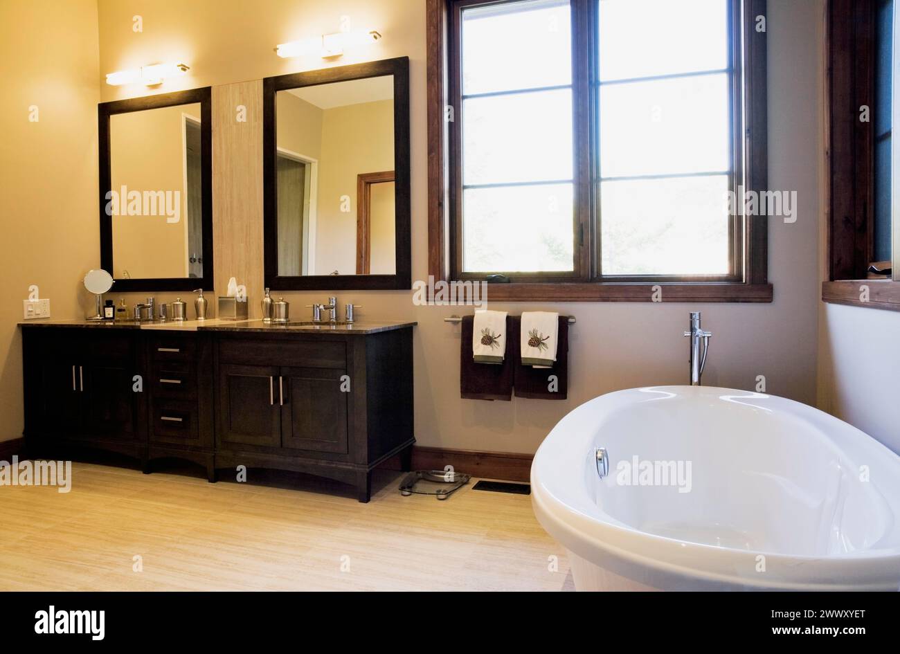 Hölzerne Waschtische und freistehende ovale Badewanne im Hauptbadezimmer in Erweiterung im luxuriösen Blockhüttenhaus, Quebec, Kanada Stockfoto