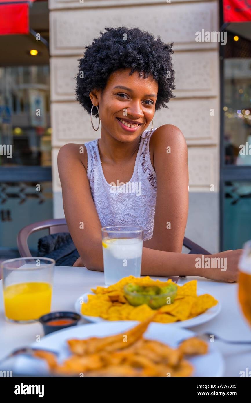 Niedliche Schönheit afrikanische Frau, die vor der Kamera lächelt und in einem mexikanischen Fast-Food-Restaurant sitzt Stockfoto