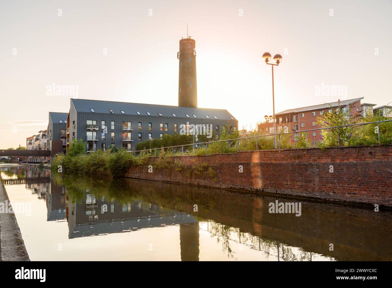 Moderne Apartmenthäuser in einer Sanierung entlang eines Kanals unter klarem Himmel bei Sonnenuntergang im Sommer Stockfoto