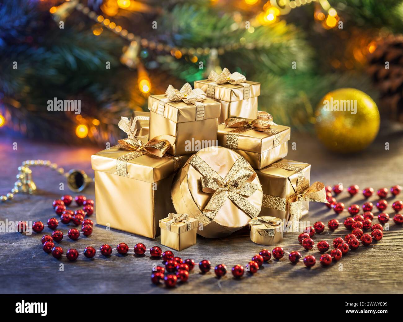 Weihnachtsgeschenke als Symbol für Weihnachtsglück und Wunder. Glitzernde Lichter auf dem Weihnachtsbaum im Hintergrund. Stockfoto