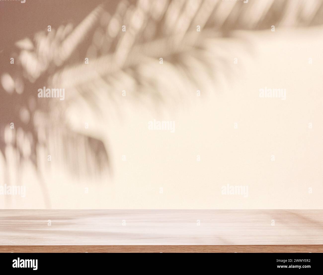 Verschwommener Schatten tropischer Palmenblätter auf beigefarbener Wand und Tischplatte im Vordergrund. Sommerkonzept. Stockfoto