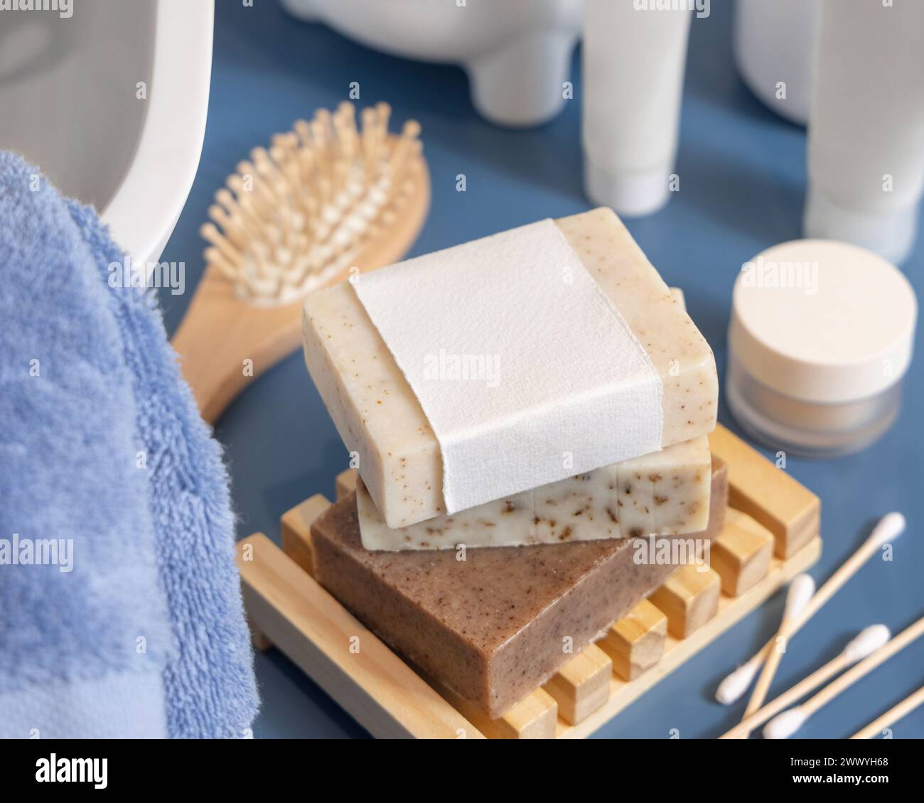 Seifenleiste mit leerem Etikett auf blauer Badezimmerarbeitsfläche in der Nähe des Waschbeckens, Verpackungsmodell, Kopierraum. Naturhygieneprodukte und Kosmetik Stockfoto