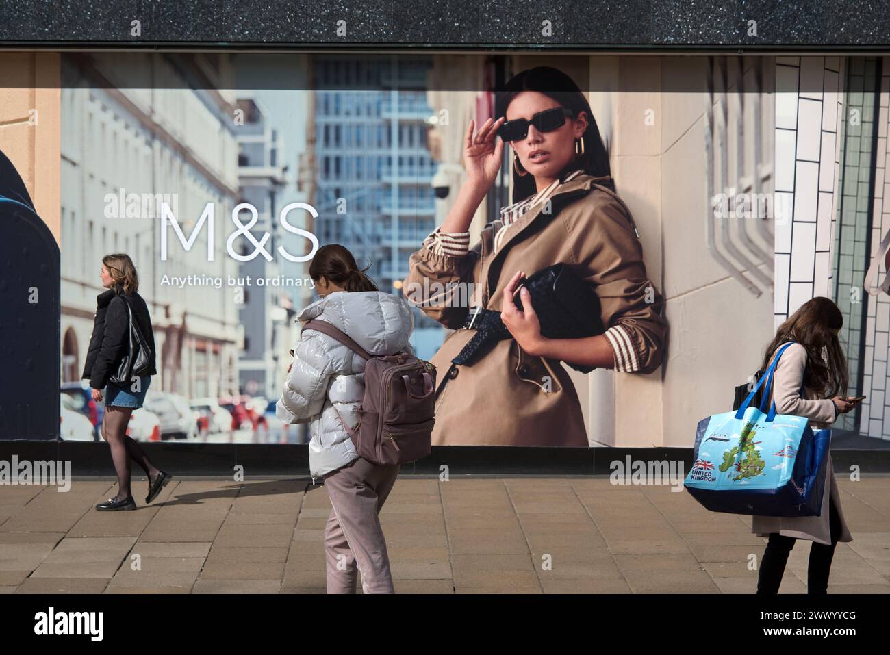 Drei junge Frauen, die an einem Marks & Spencer-Geschäft in der Princes Street, Edinburgh, Schottland, Großbritannien, vorbeilaufen. Stockfoto