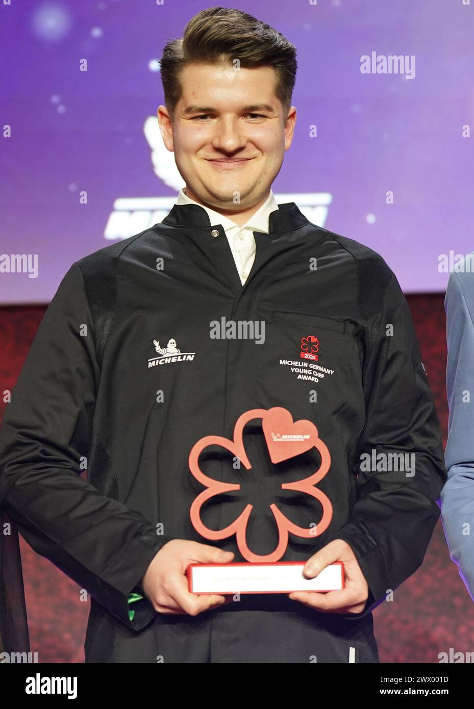 Hamburg, Deutschland. März 2024. Der 1-Sterne-Koch Cedric Staudenmayer vom „Restaurant Cedric“ in Weinstadt vergibt seinen Young Chef Award auf der Bühne während der Preisverleihung der Michelin-Sterne 2024 für deutsche Restaurants in der Handelskammer. Der diesjährige Michelin Guide bietet 340 Restaurants, die in den letzten Monaten einen oder mehrere Sterne verdient haben, darunter zehn drei-Sterne-Restaurants. Quelle: Marcus Brandt/dpa/Alamy Live News Stockfoto