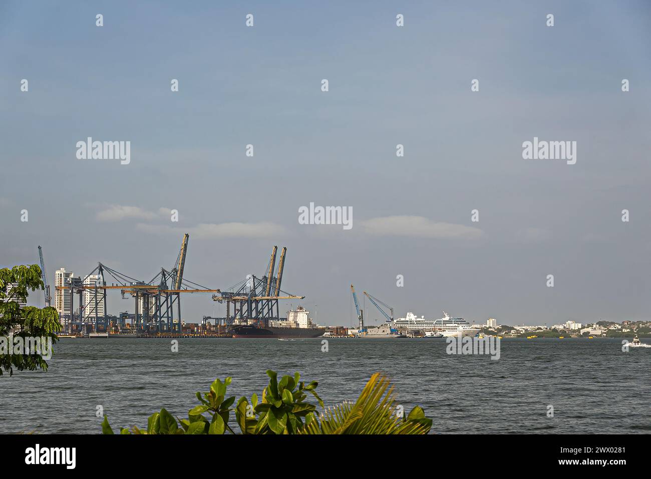Cartagena, Kolumbien - 25. Juli 2023: Weißes Kreuzfahrtschiff am Dock neben dem SPRC-Containerterminal im Hafen unter blauer Wolkenlandschaft Stockfoto