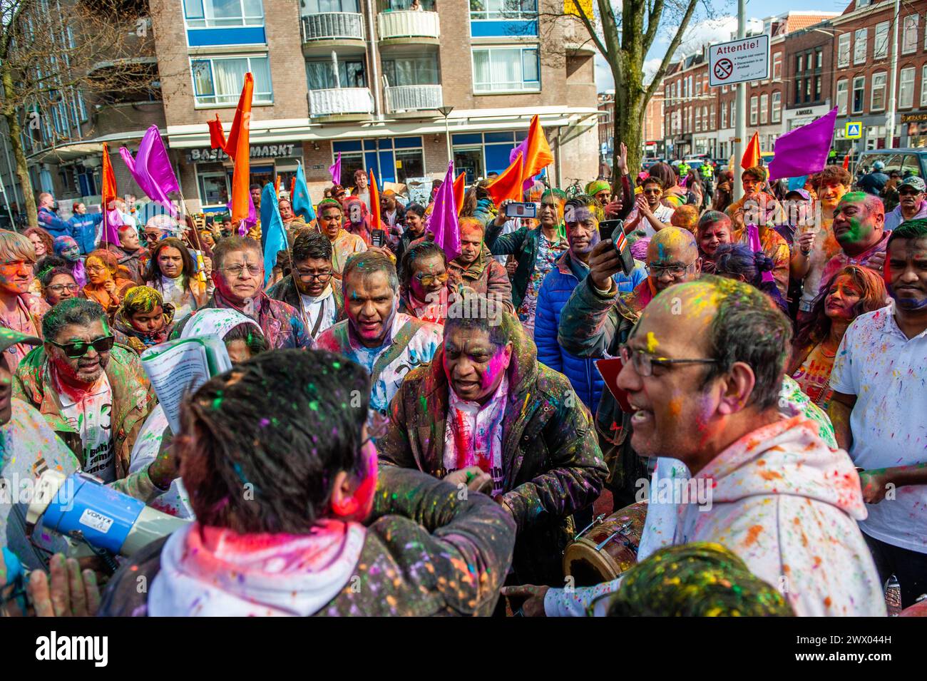 Eine indische Musikband spielt umgeben von Menschen. Millionen von Menschen weltweit feiern das jährliche Holi Hangámá Festival, auch bekannt als das Festival der Farben, was bedeutet, die Ankunft des Frühlings zu feiern. In den Haag, wo die größte indische Bevölkerung Europas zu finden ist, fand im multikulturellen Viertel Transvaal eine große Feier statt, wo die Teilnehmer buntes Pulver auf sich und einander warfen. Die Leute feierten dieses Ereignis, indem sie in einer farbenfrohen Prozession durch die Nachbarschaft gingen und sangen und tanzten. Stockfoto