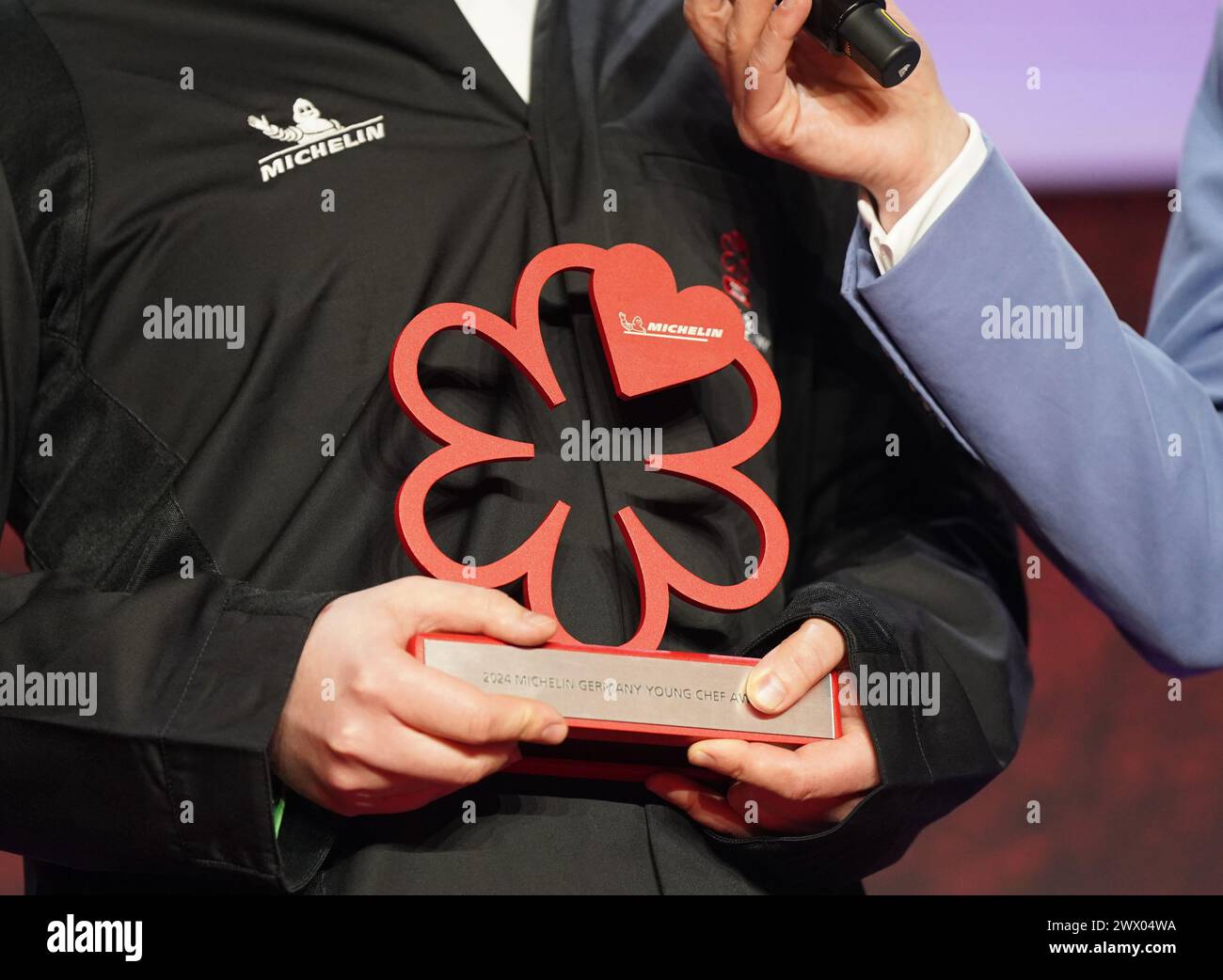 Hamburg, Deutschland. März 2024. Bei der Preisverleihung der Michelin Stars 2024 für deutsche Restaurants in der Handelskammer steht ein Gewinner mit einem symbolischen Stern auf der Bühne. Der diesjährige „Guide Michelin“-Restaurantführer listet 340 Restaurants auf, die in den letzten Monaten einen oder mehrere Sterne verdient haben, darunter zehn drei-Sterne-Restaurants. Quelle: Marcus Brandt/dpa/Alamy Live News Stockfoto