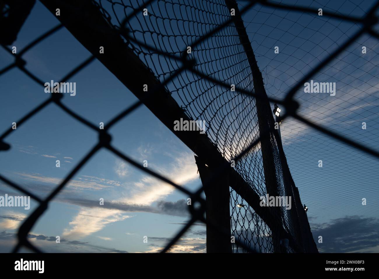 Netz und Zaun eines alten verlassenen Sportplatzes gegen Sonnenuntergang. Sportausrüstung. Stockfoto