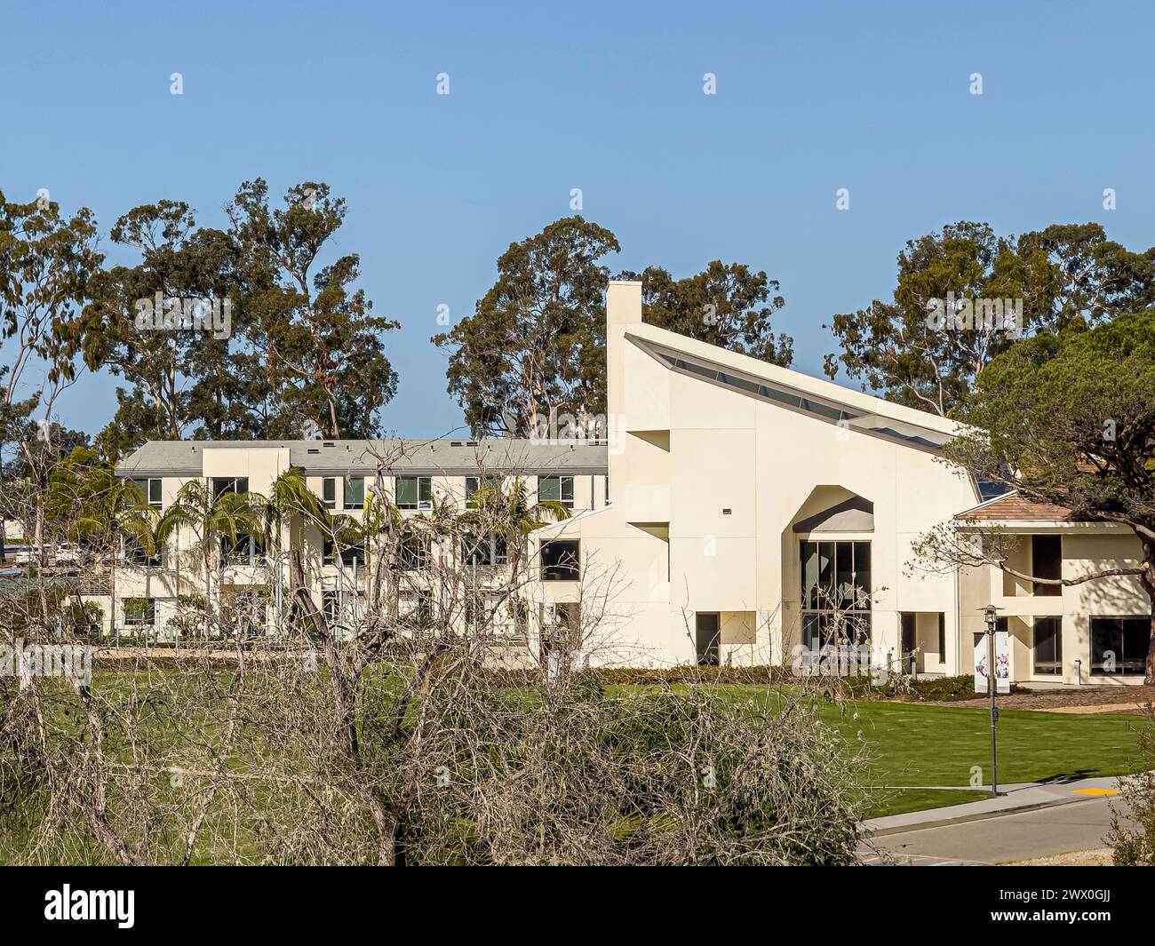 Santa Barbara, Kalifornien, USA - 17. März 2024: UCSB, The Club and Guest House Ostfassade unter blauem sonnigem Himmel mit grünem Laub dahinter Stockfoto