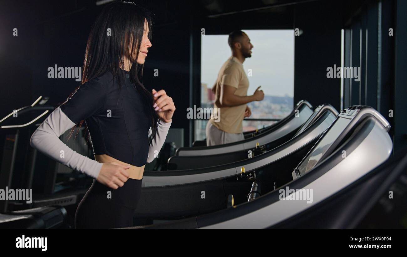 Motivierte Sportler Läufer Cardio-Training auf Laufbändern aktives Workout im Fitnessclub Frauen und Mann Paar Athleten laufen Sprint-Jog in der Dunkelheit Stockfoto