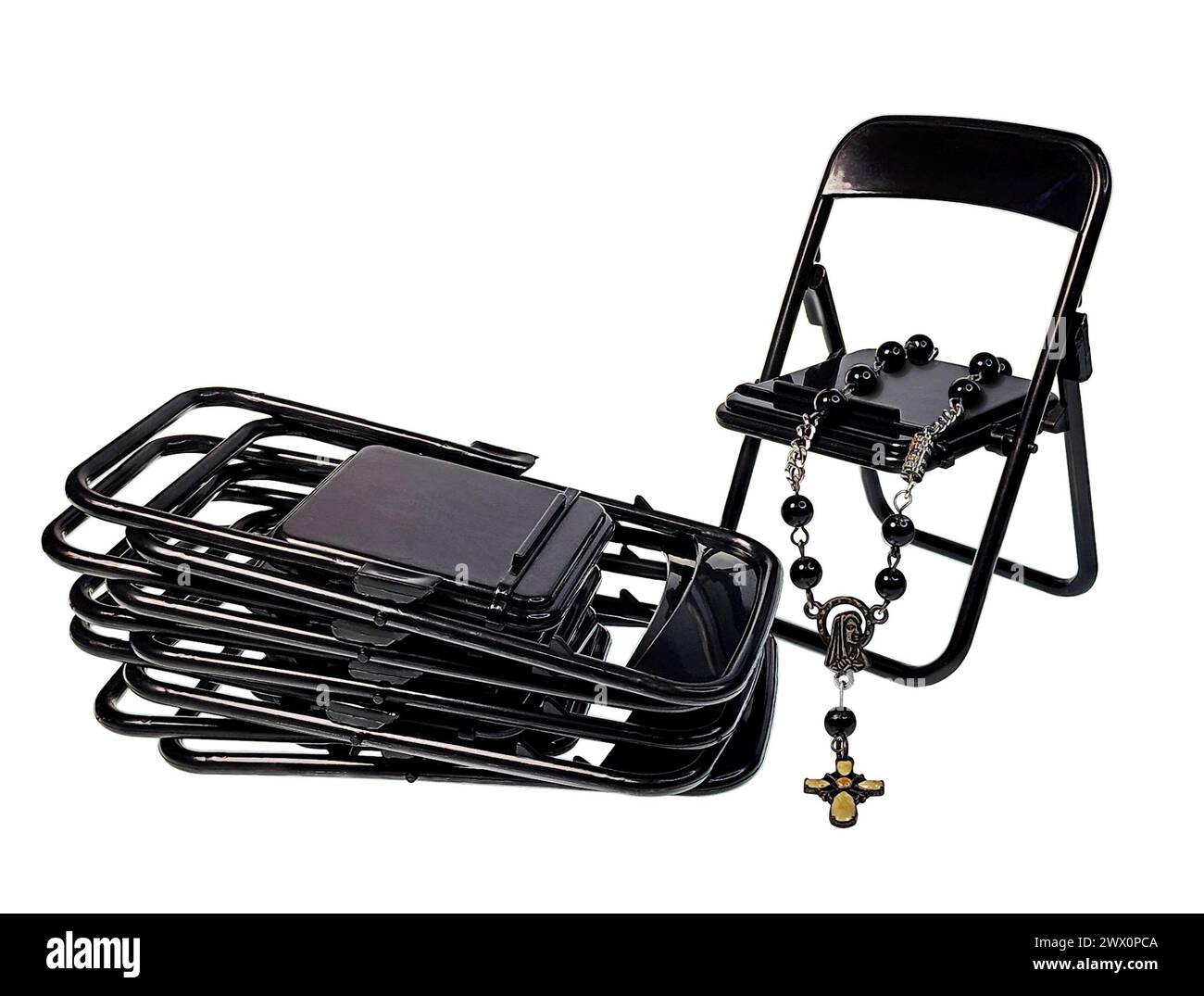 Ein Satz schwarzer Klappstühle im Kirchenkeller mit Rosenkranz Stockfoto