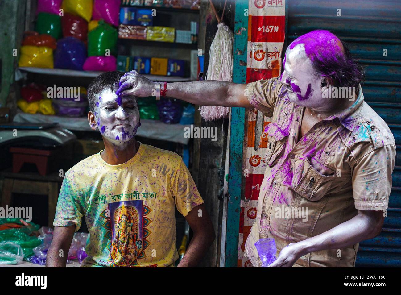 Dhaka, Bangladesch. März 2024. Ein Mann, der das Gesicht eines Jungen aus der hinduistischen Gemeinde schminkt, um das Dol Purnima Festival zu feiern, das als Holi Festival auf dem Sakhari Basar bekannt ist. Am 26. März 2024 in Dhaka, Bangladesch. (Kreditbild: © Nahid Hasan/OKULARIS via ZUMA Press Wire) NUR REDAKTIONELLE VERWENDUNG! Nicht für kommerzielle ZWECKE! Stockfoto