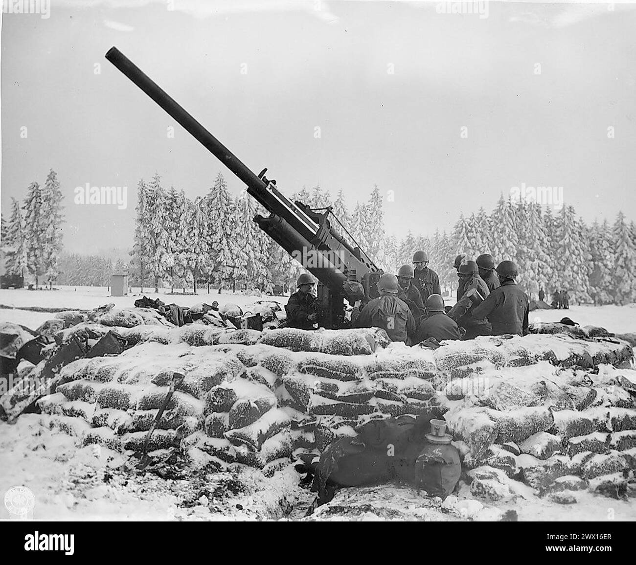 Originalunterschrift: Geschützbesatzung der „Black Widow“, 90-mm-Flugabwehrkanone, die in Bastogne, Belgien, gegraben wurde und dabei ist, auf feindliches Flugzeug zu feuern, das in der Gegend gesichtet wurde. Batterie B 217. BN (Radar) Bastogne. CA. 1945 Stockfoto