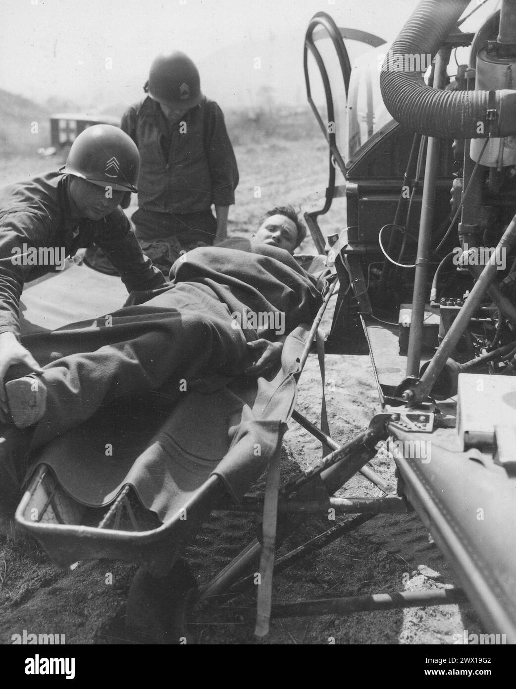 Ein verwundeter Amerikaner wird auf einen Hubschrauber in der Sammelstation des 21. Infanterieregiments in Painmal, Korea, eine Meile südlich des 38. Breitengrades, gebracht, um in ein Basiskrankenhaus ca. 1951 Stockfoto