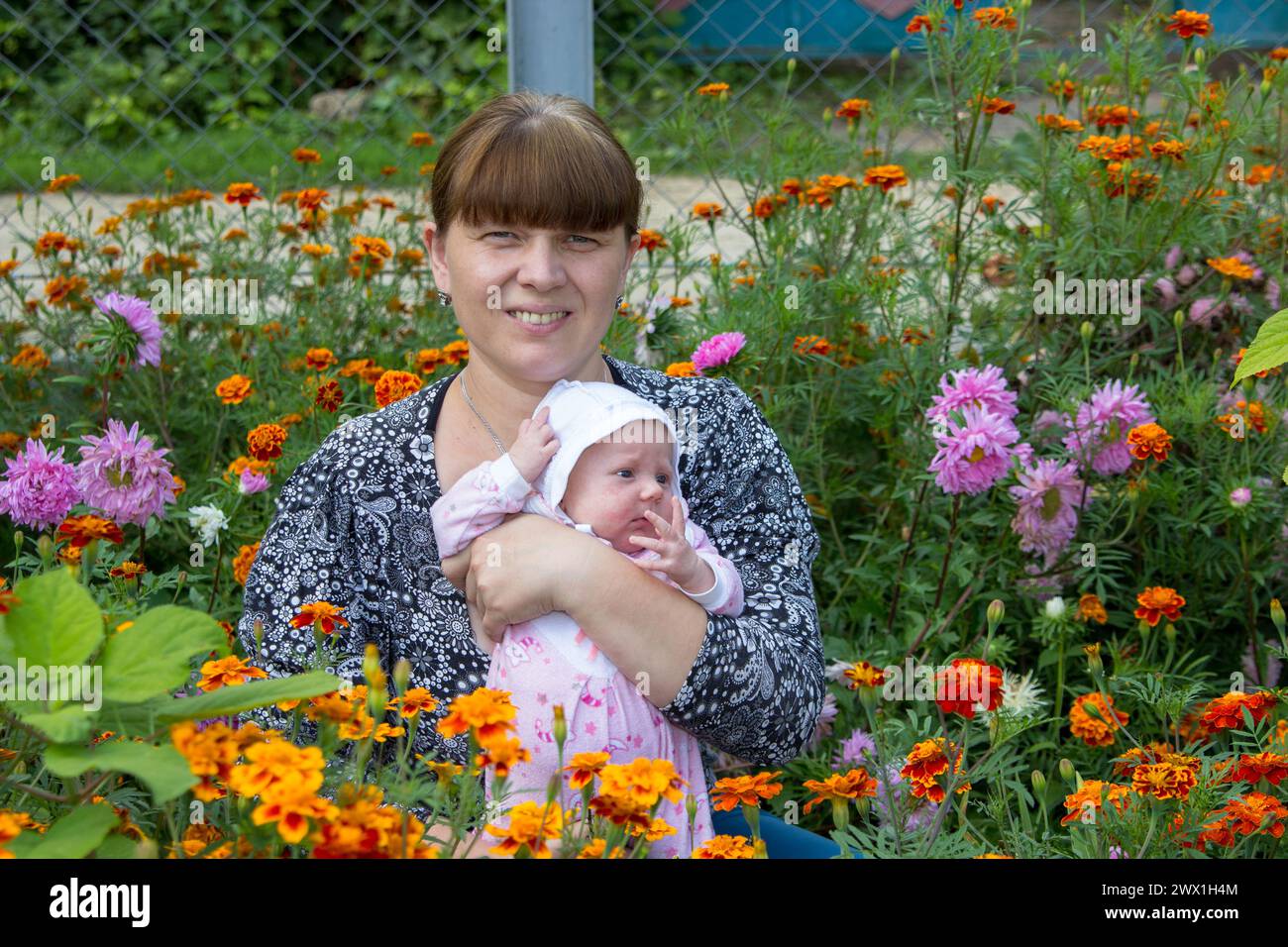 Im blühenden Garten sitzt die Mutter im Herbst mit dem Baby Stockfoto