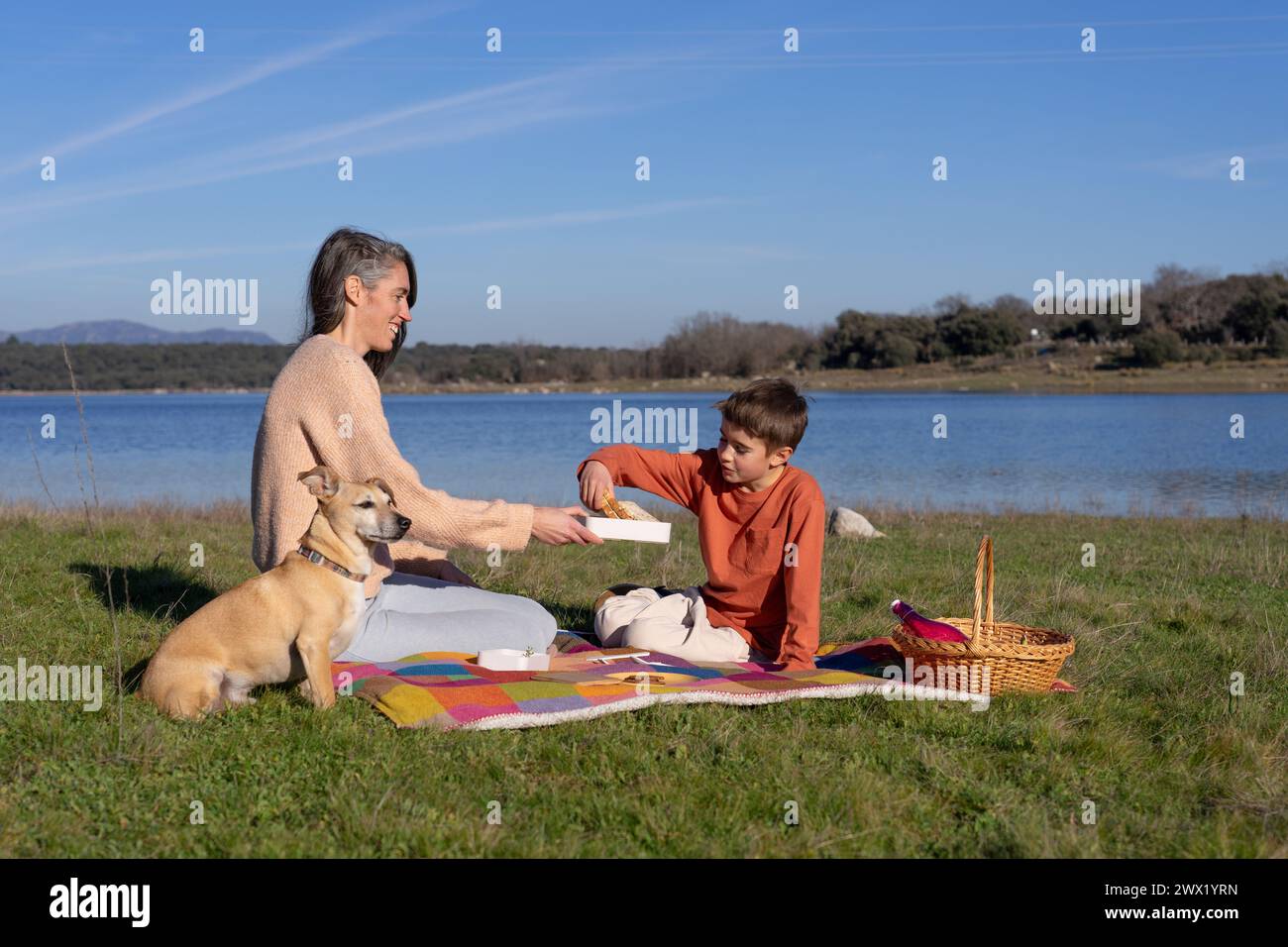 Mutter und Sohn machen ein Picknick am See mit ihrem Hund Stockfoto