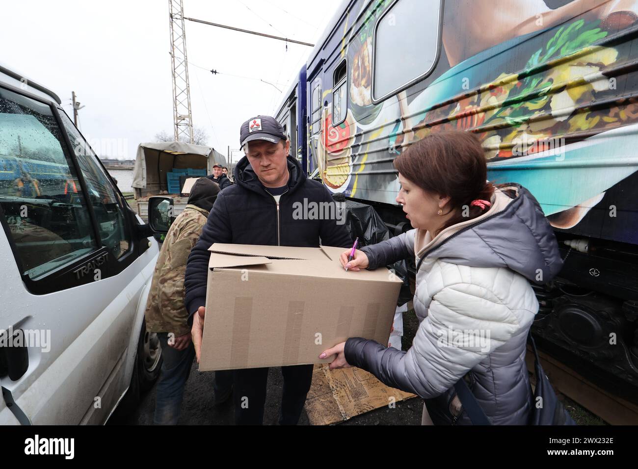 CHARKIW, UKRAINE - 26. MÄRZ 2024 - Freiwillige und Mitarbeiter der ukrainischen Roten Kreuz-Gesellschaft erhalten Mittagessen für Patienten von Krankenhäusern und Binnenvertriebenen, die in Herbergen des Food Train leben, die in der Stadt angekommen sind und an Stromausfällen leiden, die durch russische Angriffe auf kritische Infrastrukturen verursacht wurden; Charkiw, Nordost-Ukraine. Der Food Train ist ein Projekt der Ukrainischen Eisenbahn (Ukrzaliznytsia), das mit der Gründung des US-amerikanischen Milliardärs Howard Buffett umgesetzt wurde. Der Küchenzug kann mehr als 10.000 Portionen Essen pro Tag produzieren, selbst wenn es keinen Strom gibt. Stockfoto