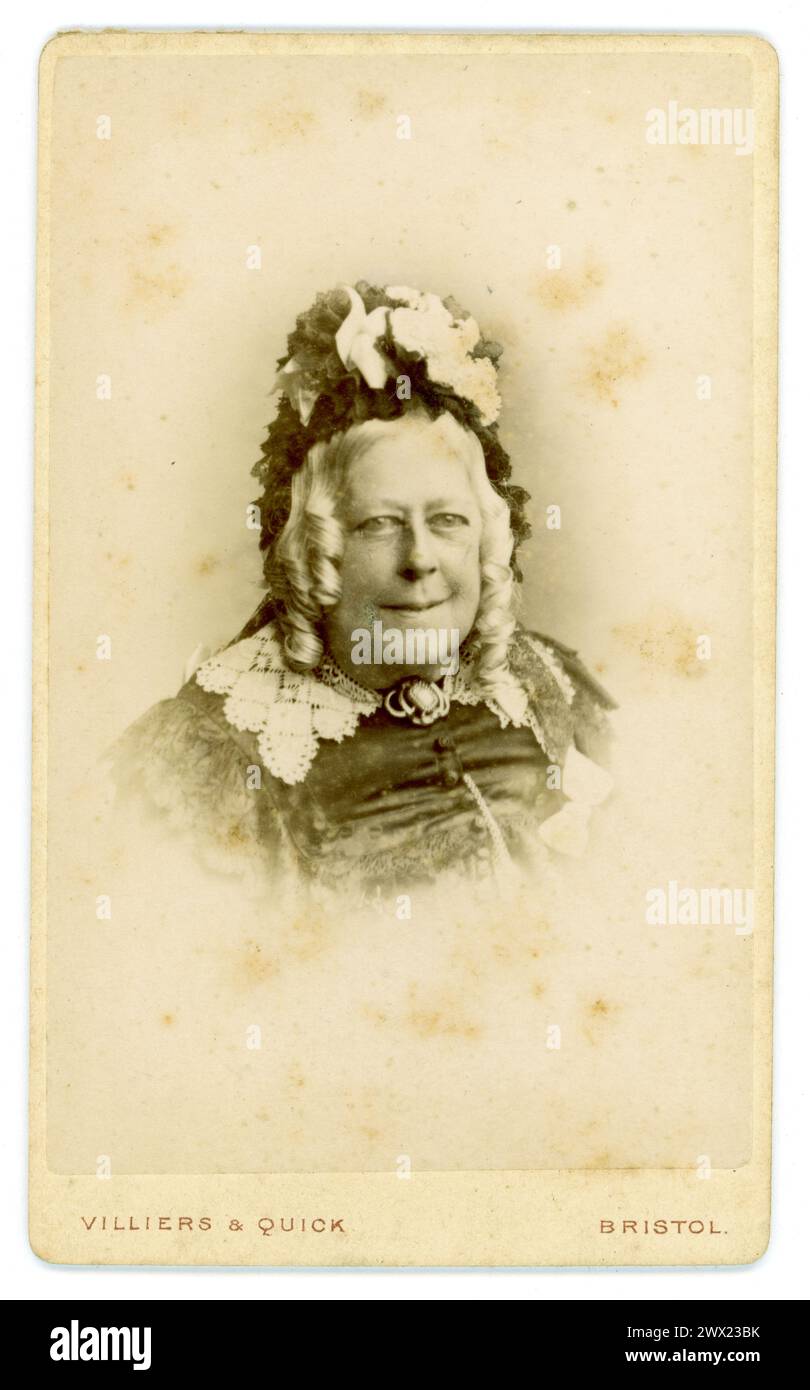 Original viktorianische Carte de Visite (Visitenkarte oder CDV) Porträt einer älteren, lächelnden, nett aussehenden viktorianischen Dame mittleren Alters, viktorianische Frau, in schwarzer Kleidung und mit einer mit Spitze beschnittenen Mütze, langen gelockten grauen Haaren, Studio von Villiers and Quick, Bristol, Großbritannien um 1870 Stockfoto