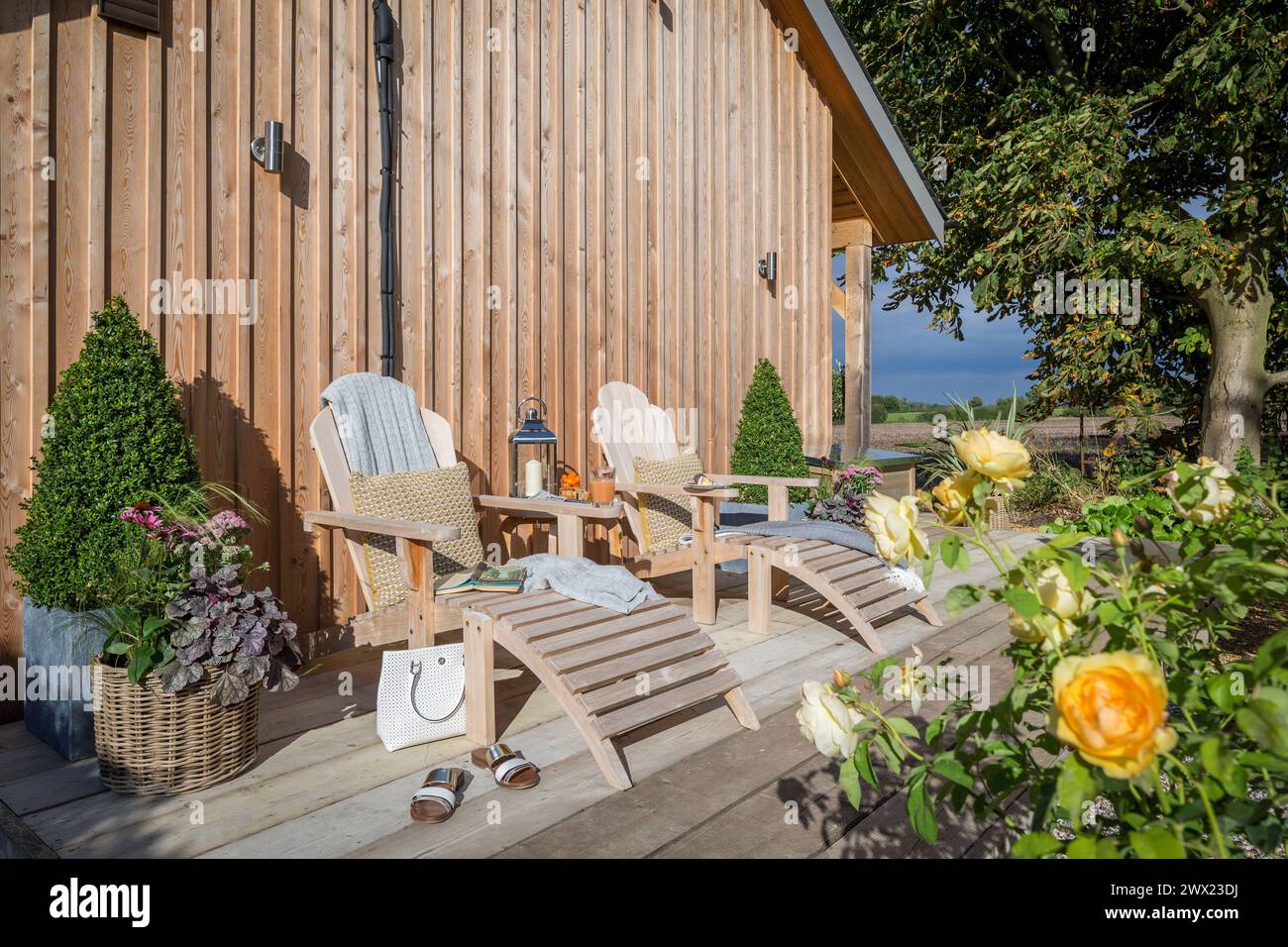 Hölzerne Liegestühle auf einer hölzernen Terrasse im Garten eines hölzernen Ferienhauses in Suffolk, Großbritannien Stockfoto