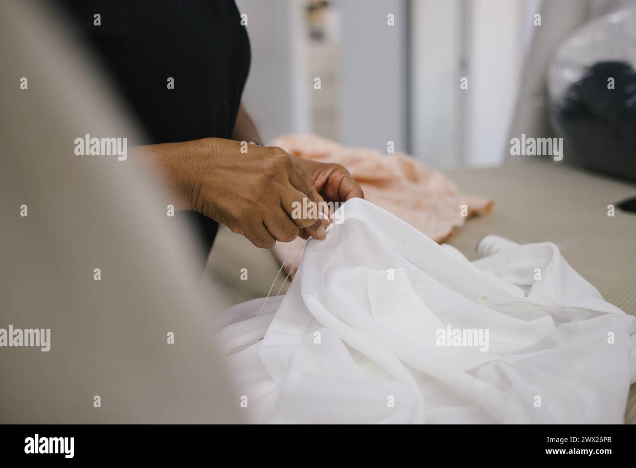 Frau, die Stoffe im Bekleidungsprozess auswählt. Umkleideraum, Textilindustrie Stockfoto