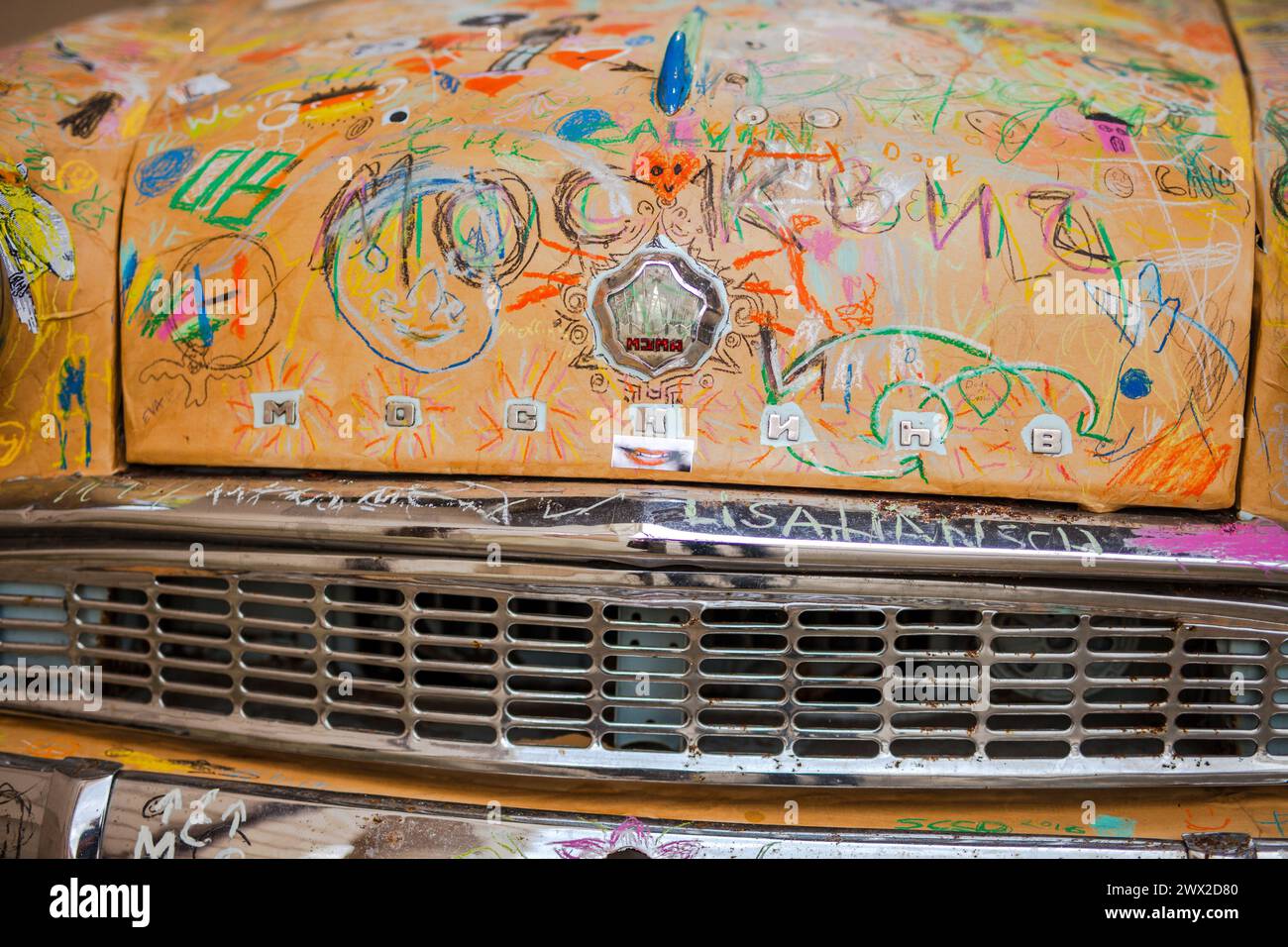 Nahaufnahme einer bunt mit Graffiti verzierten Moskvitch-Autohaube mit Emblem. Stockfoto