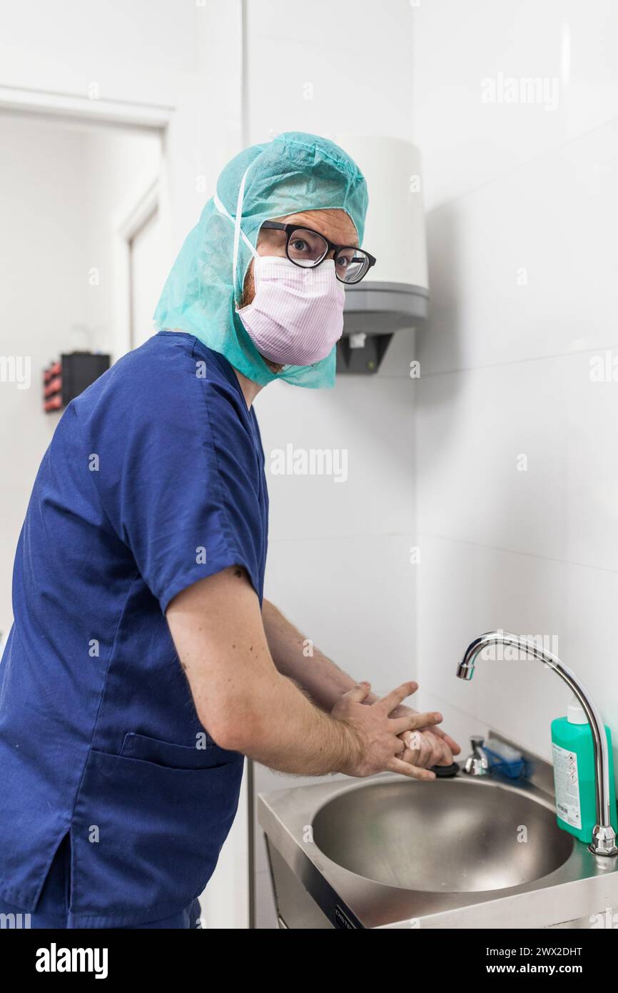 Tierarzt-Chirurg in Epi-Kleidung zur Vorbereitung der Handwaschung im Klinikwaschbecken Stockfoto