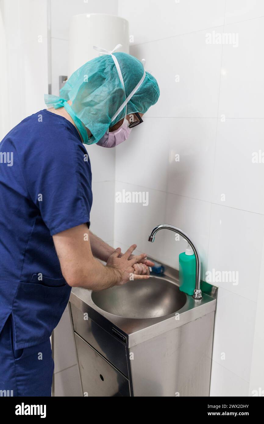 Tierarzt-Chirurg in Epi-Kleidung zur Vorbereitung der Handwaschung im Klinikwaschbecken Stockfoto