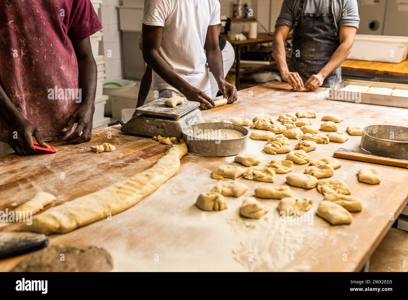Nicht erkennbare multiethnische Gruppe von Kollegen, die in einer Brotfabrik arbeiten und die Lehrlinge unterrichten Stockfoto