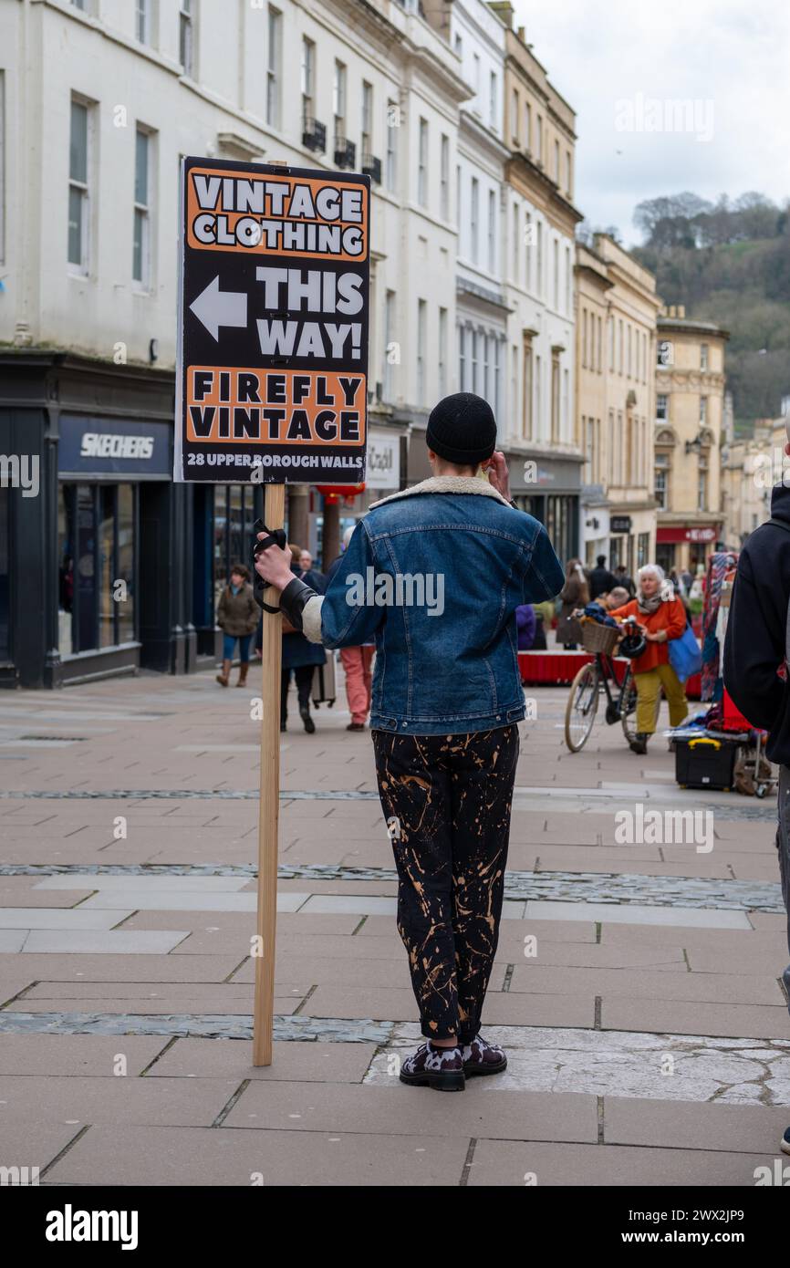 Mann mit einem Schild, das Vintage-Kleidung in Bath, Großbritannien, anwirbt (März 24) Stockfoto