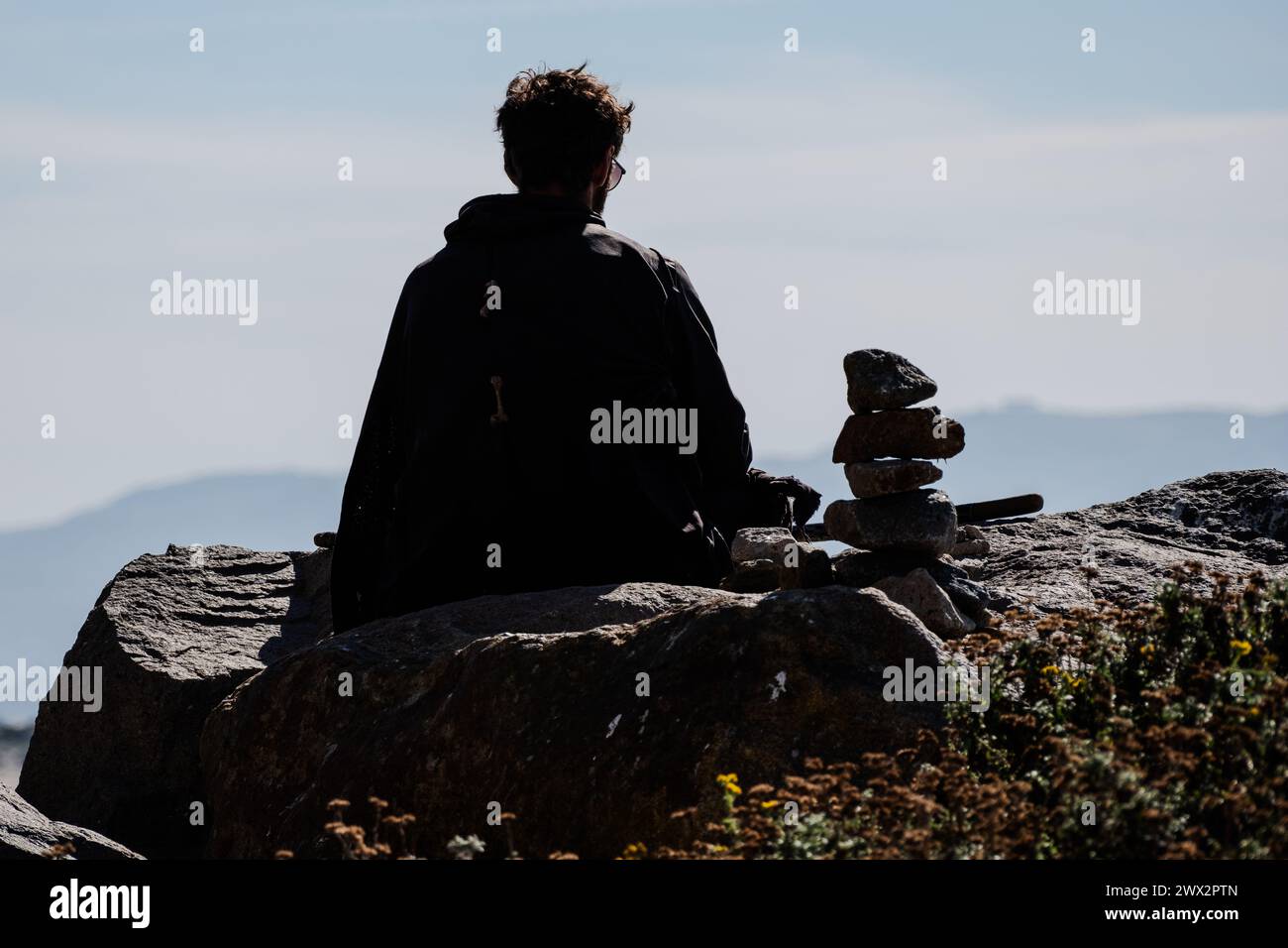 Mann sitzt allein auf Felsen in Morro Rock und Morro Bay, Pazifik, Morro Bay, Kalifornien, USA. Stockfoto