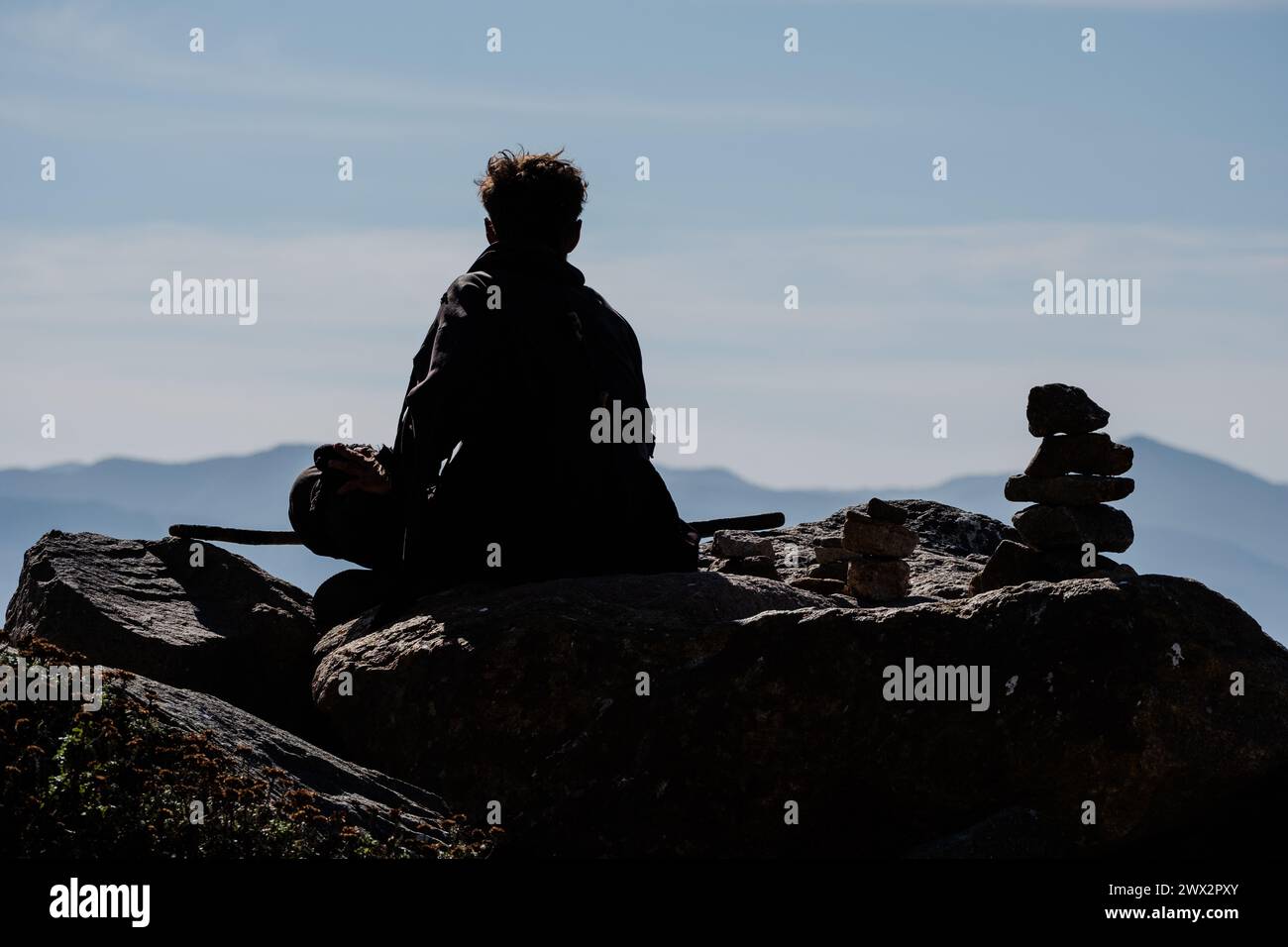 Mann sitzt allein auf Felsen in Morro Rock und Morro Bay, Pazifik, Morro Bay, Kalifornien, USA. Stockfoto