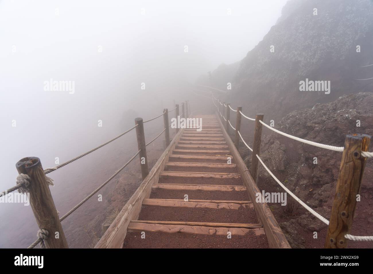 Holztreppen an einem nebeligen Tag auf dem Fußgängerweg zum Gipfel des Vulkans vesuv. Neapel, Italien Stockfoto