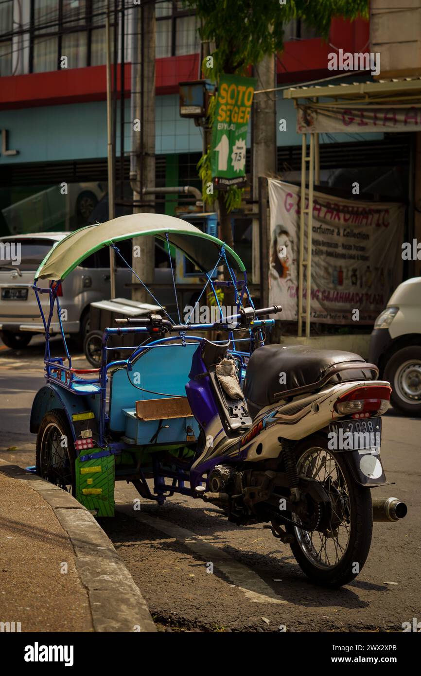 Typische indonesische öffentliche Verkehrsmittel sind modifizierte, motorisierte Becak oder Pedicab, die tagsüber am Straßenrand parken Stockfoto