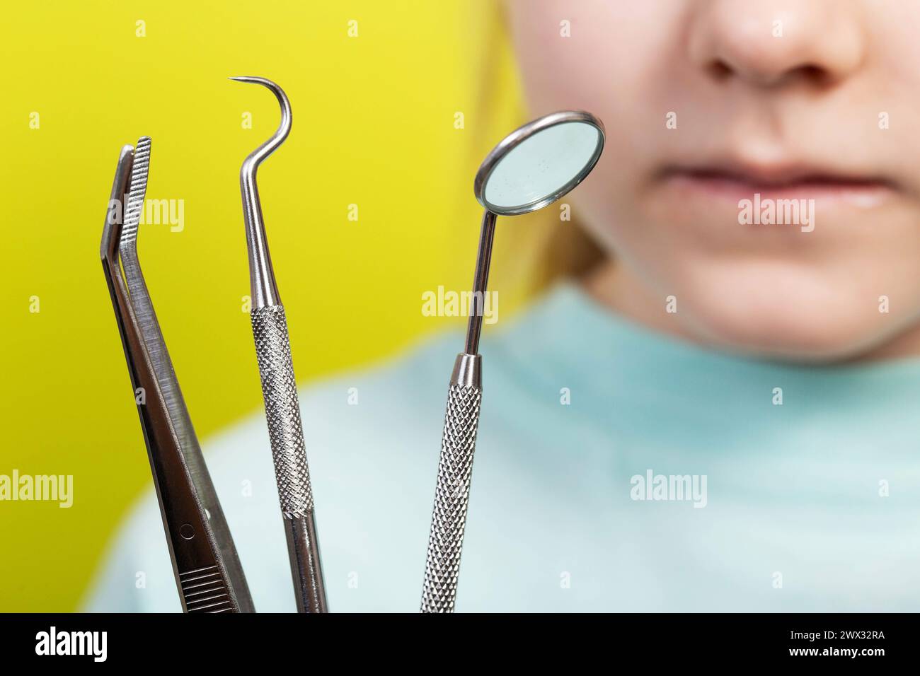 Zahnärztliche Instrumente vor dem Hintergrund des Mundes eines siebenjährigen Mädchens. Chirurgisches zahnmedizinisches Konzept, Entfernung von Säuglingszähnen und Behandlung von Ca Stockfoto