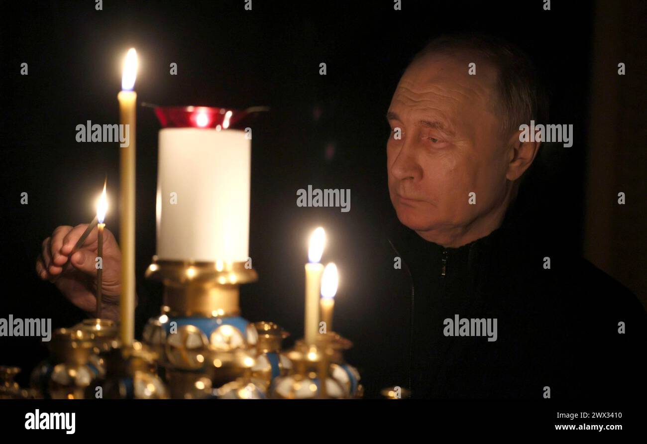 Novo-Ogaryovo, Russland. März 2024. Der russische Präsident Wladimir Putin zündet eine Kerze zu Ehren der Menschen an, die bei dem Terroranschlag auf das Rathaus von Crocus getötet wurden. Die Residenz des Präsidenten Novo-Ogarjowo, 24. März 2024, außerhalb Moskaus, Russland. Mindestens 130 Zivilisten wurden von Terroristen des Islamischen Staates bei einem Angriff auf einen Konzertsaal getötet. Quelle: Mikhail Metzel/Kreml Pool/Alamy Live News Stockfoto