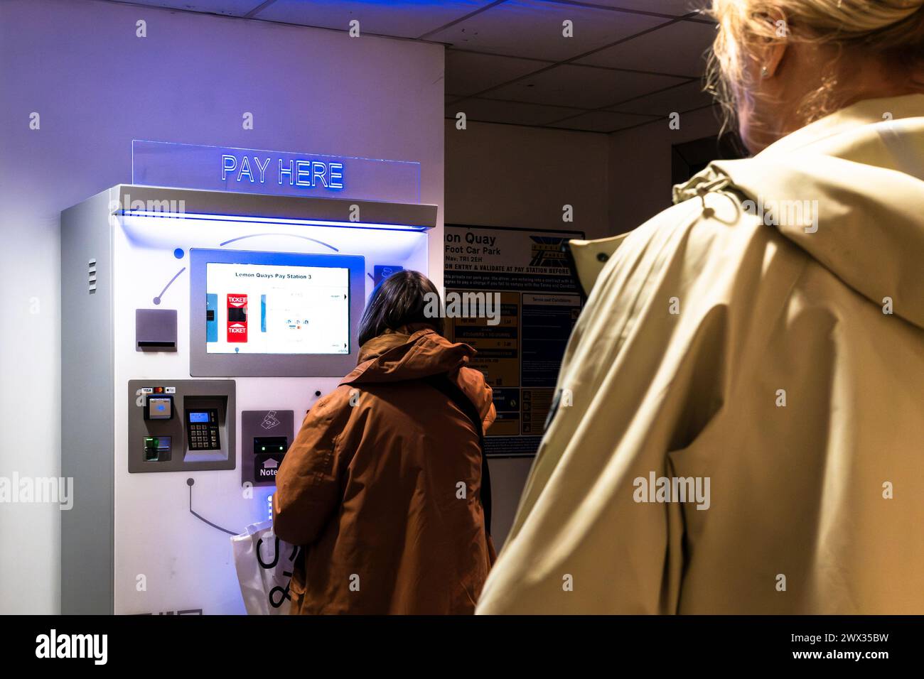 Käufer, die an einer Kassenstelle in einem Ladengeschäft im Stadtzentrum von Truro in Cornwall (Großbritannien) zahlen müssen. Stockfoto